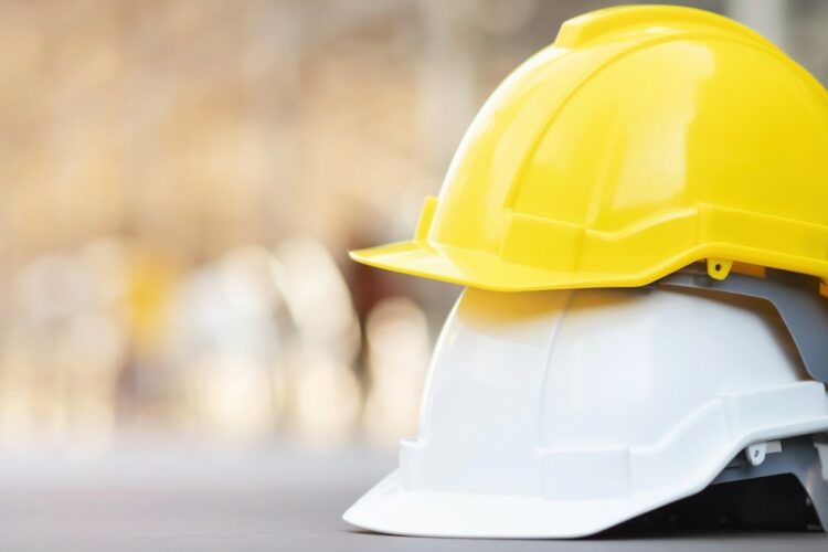 A yellow hard hat stacked on top of a white hard hat.